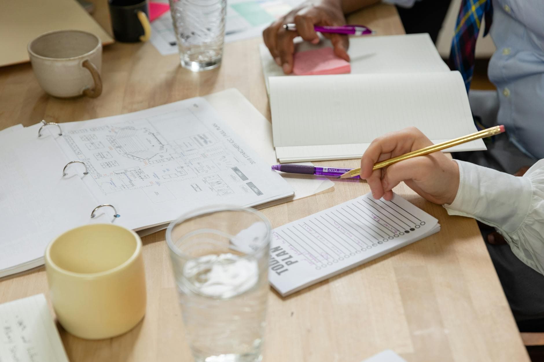 A diverse team engaged in a collaborative business meeting with notebooks and a planner.