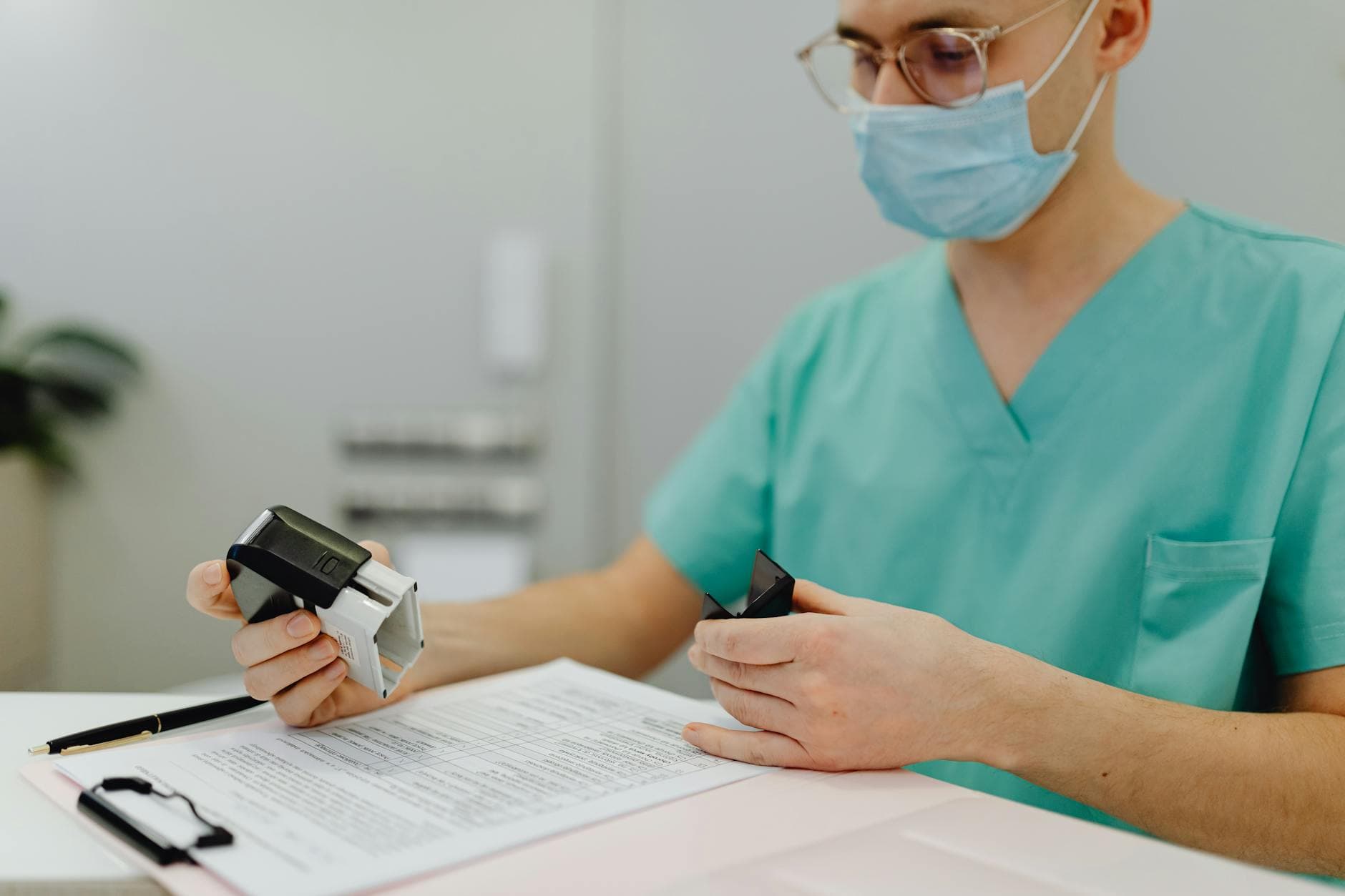 Healthcare worker in scrubs reviewing patient files with a stamp and clipboard.