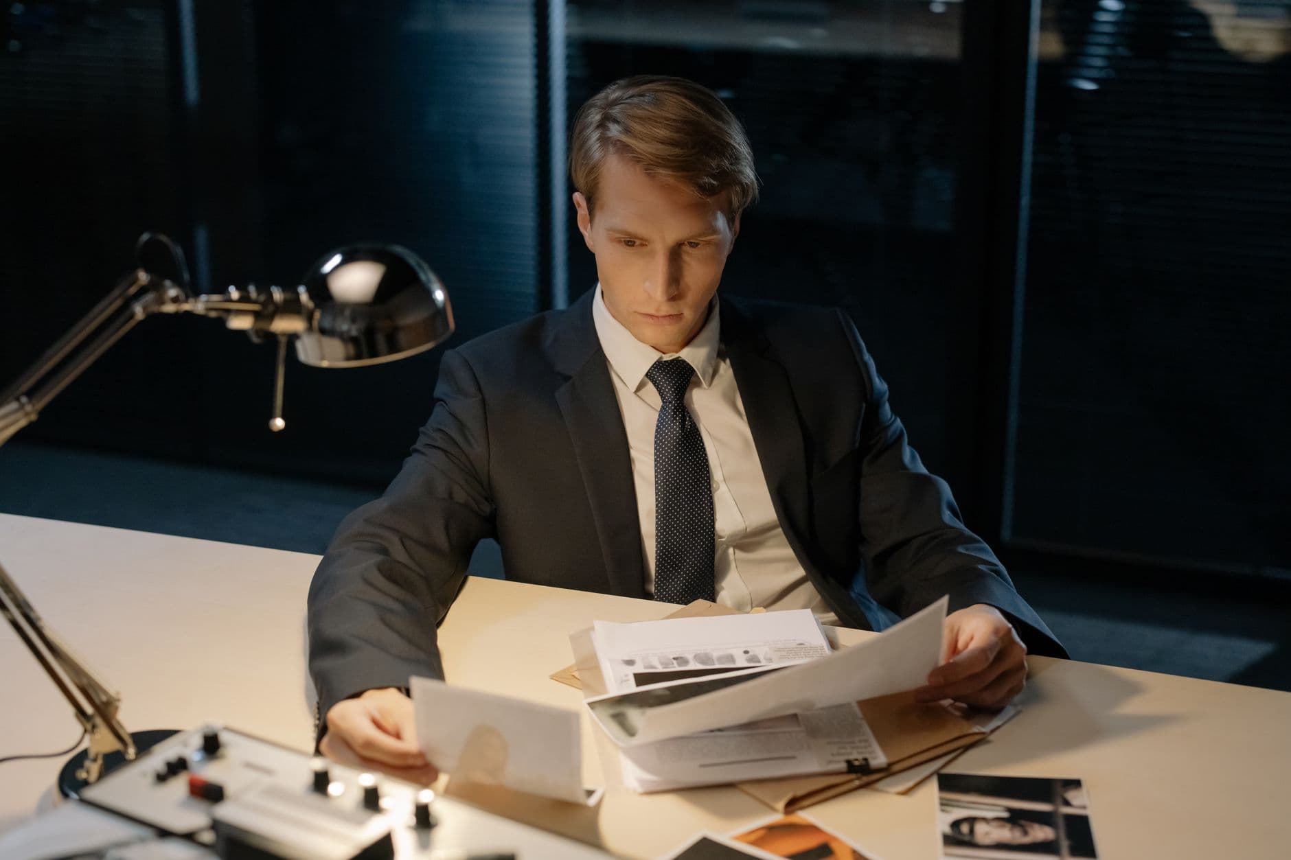 Focused investigator reviewing evidence in a dimly lit office setting.